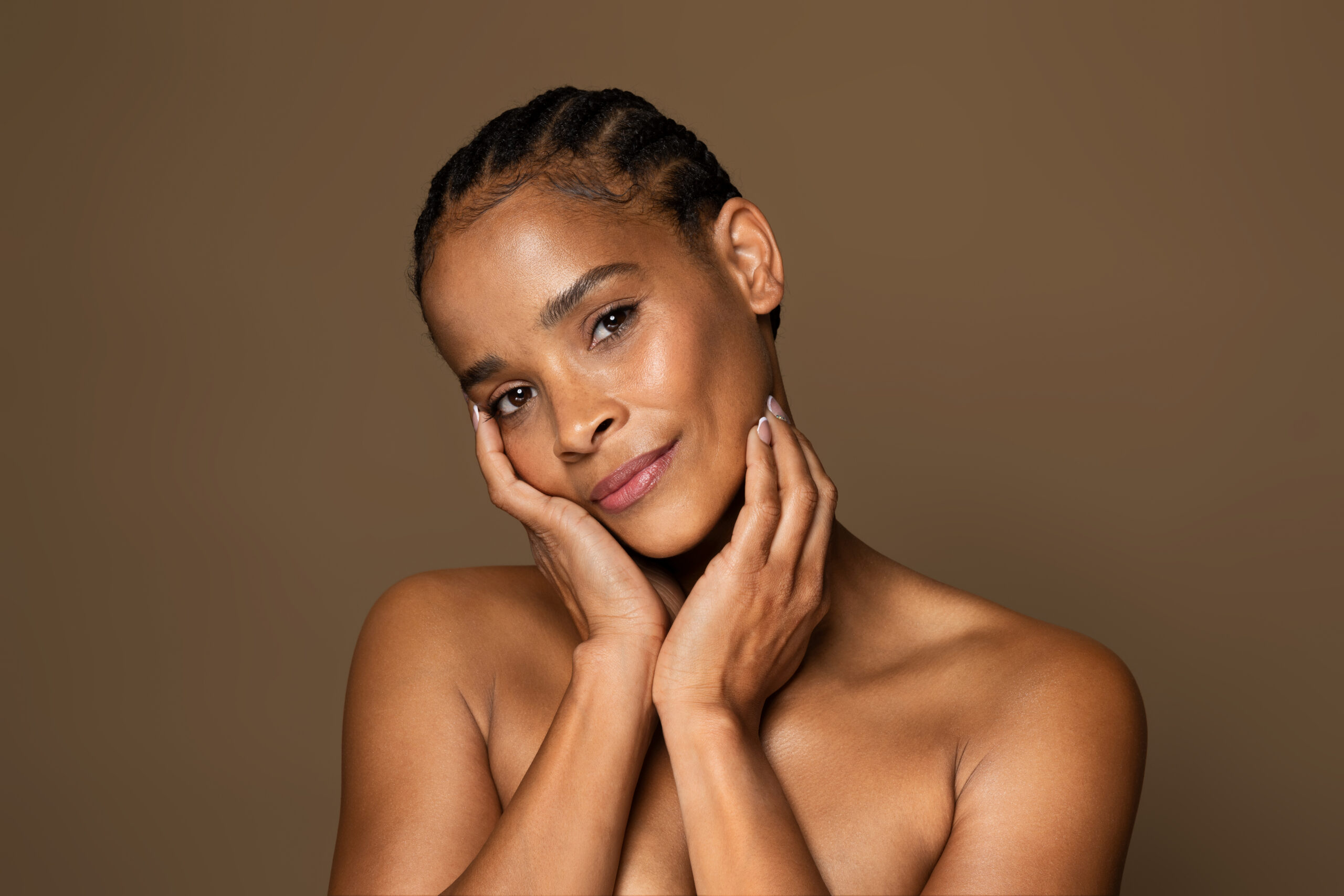 Antiage skincare concept. Beautiful black middle aged woman with flawless skin touching face and looking at camera Services Derm of Cape Cod
